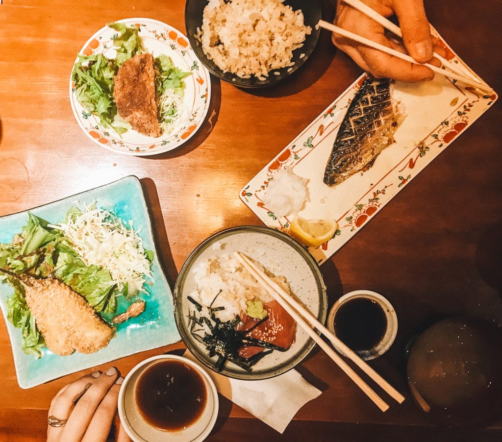 overview of a table in a restaurant in Tokyo with fish, tempura, rice, and sushi