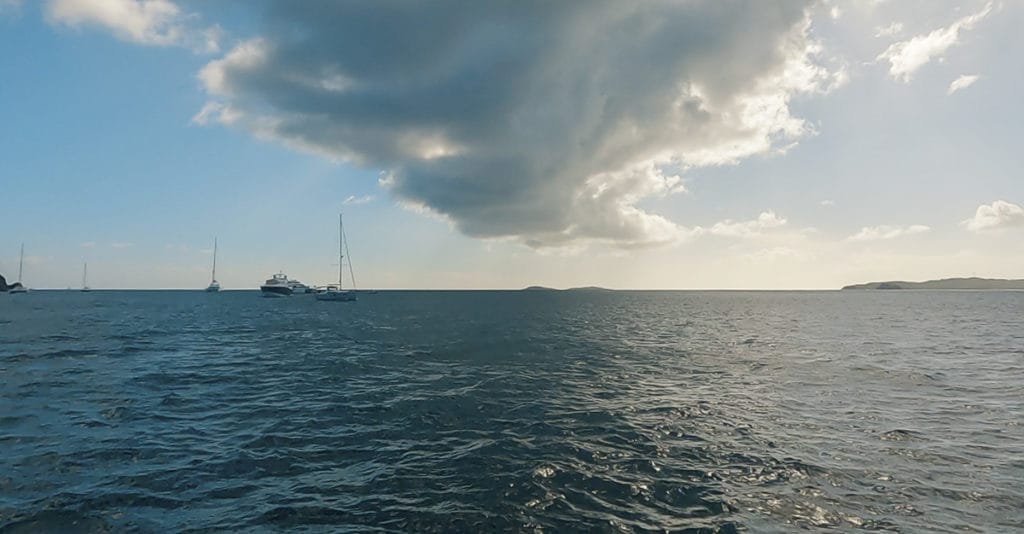 Beautiful view from the water in U.S. Virgin Islands National Park. Clouds, boats, sun, and horizon.