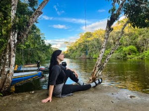 woman sitting on dock of Dolphin Ecolodge, alongside the Cuyabeno River in the Ecuadorian Amazon.